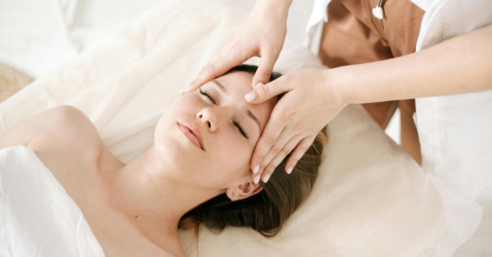 Woman receiving a relaxing face massage after treatment