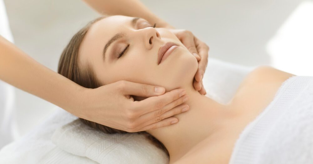 Woman with eyes closed, with her neck being gently massaged