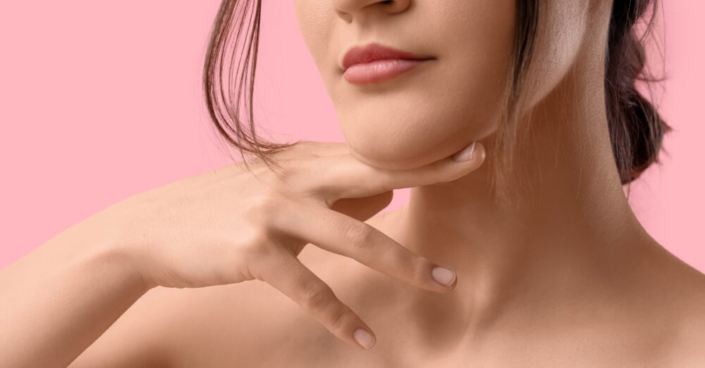 Woman touching her smooth, tightened jawline and neck after a nonsurgical neck lift treatment