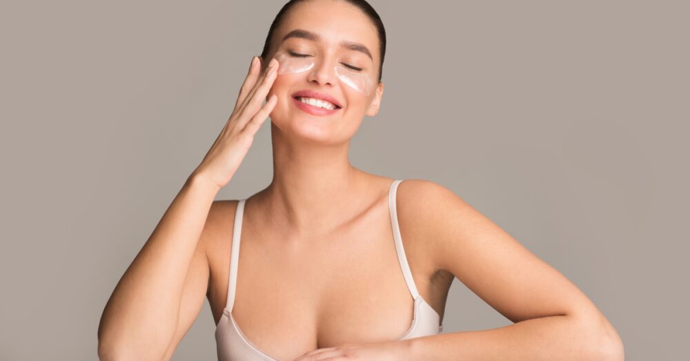 Woman touching the area under her eye while smiling with her eyes closed