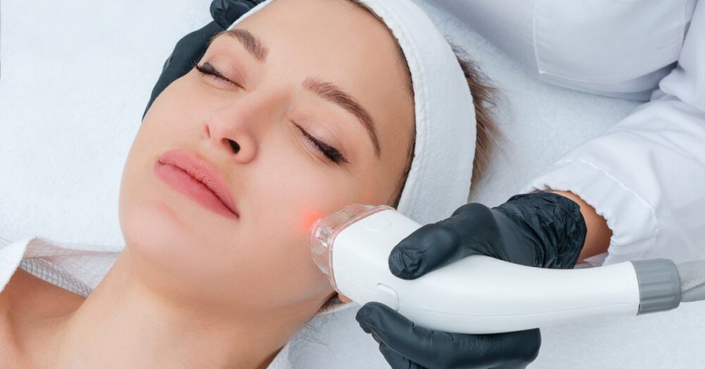 Woman with her eyes closed receiving a laser treatment on her face