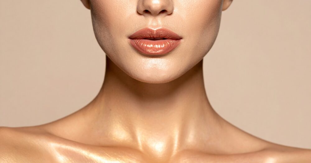 Woman with smooth, even skin tone shown from the lower face to the chest