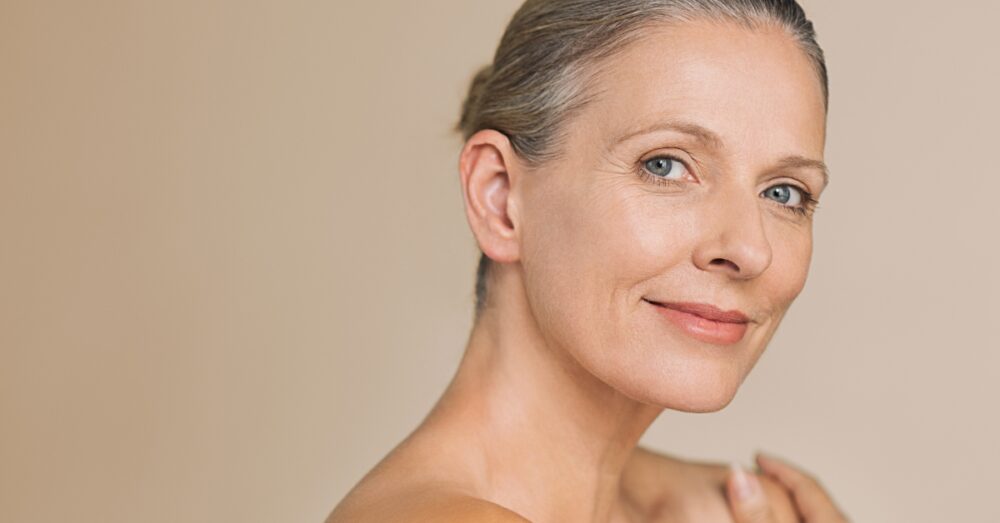 Middle aged woman smiling against a neutral background