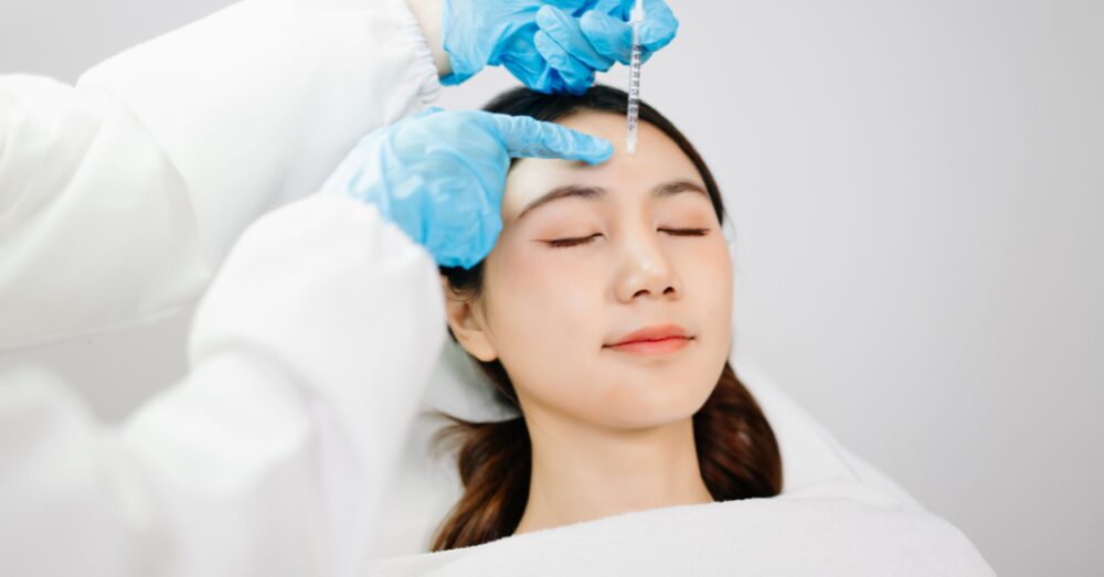 Woman receiving forehead filler in a clinical setting